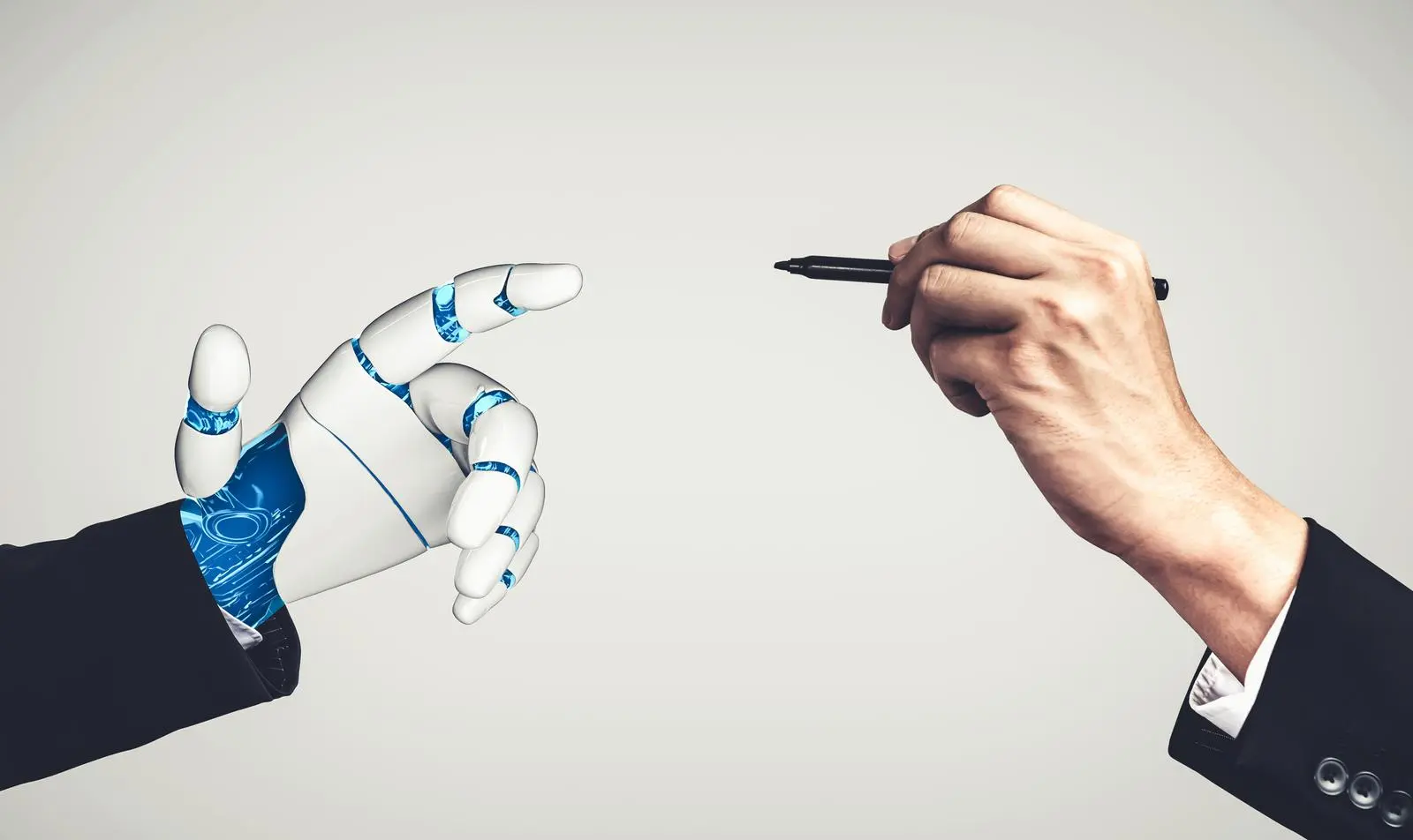 robot hand and a human hand holding a pen