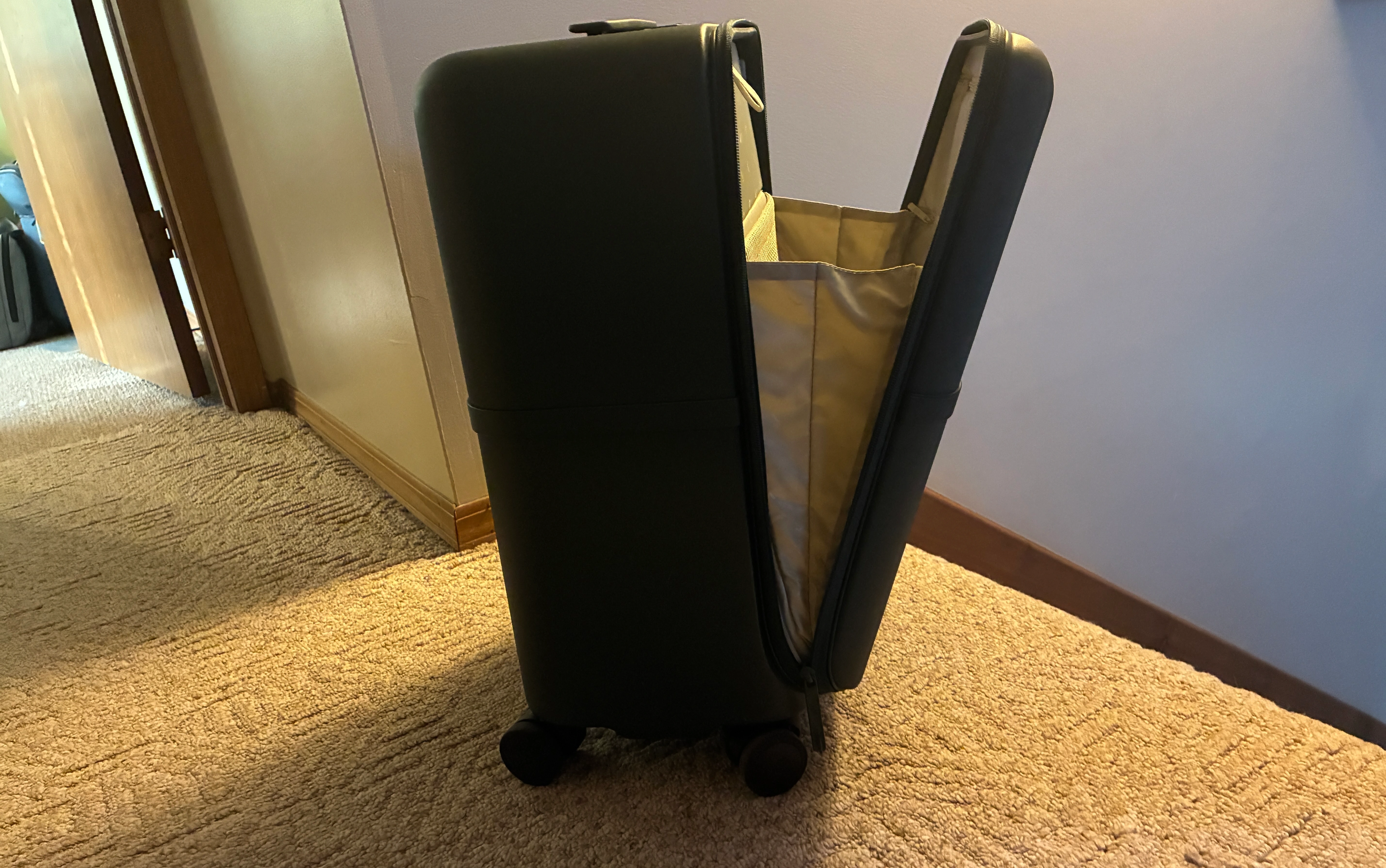 an open July Capsule Carry On Pro in a hotel room